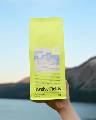 Signature Blend coffee held above a mountain lake